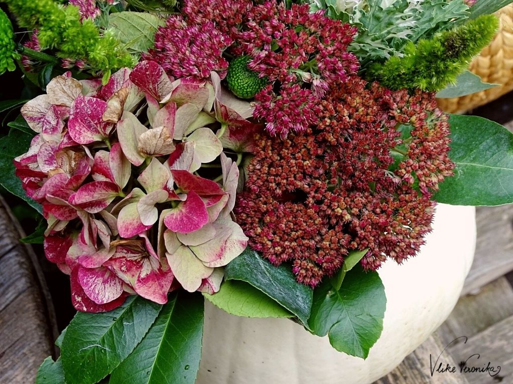 Ein Kürbis kann auch als Vase fungieren! Dekoriere ihn mit Blumen, die Du in ein Marmeladeglas stellst.