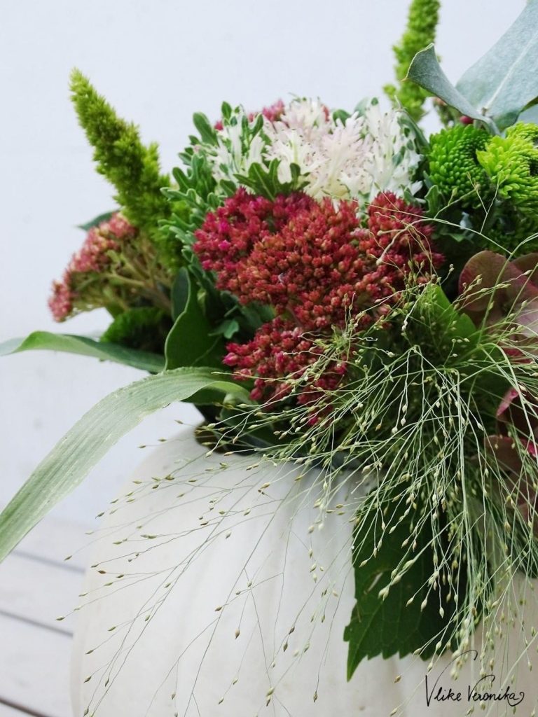 Zarte Gräser und wuchtige Herbstblumen - so schön kann Blumendeko im Kürbis sein.