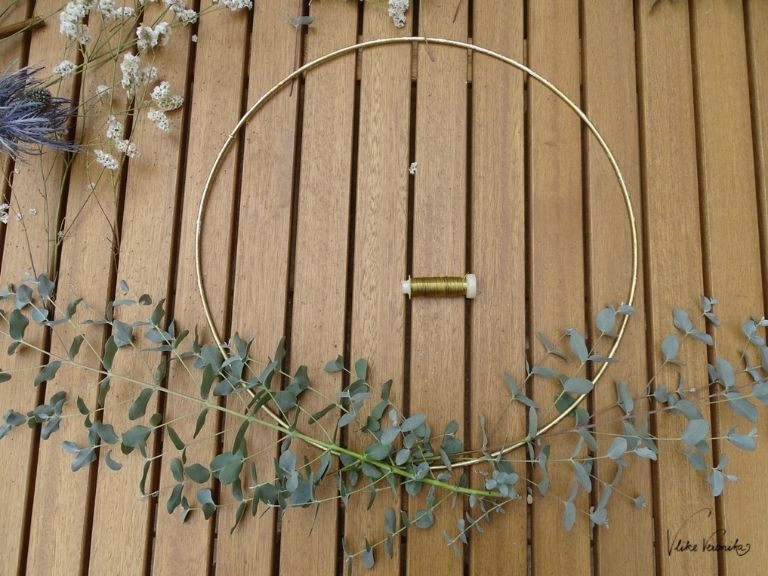 Befestige die Eukalyptuszweige auf Deinem Metallring, um einen Blumenkranz selber zu binden.
