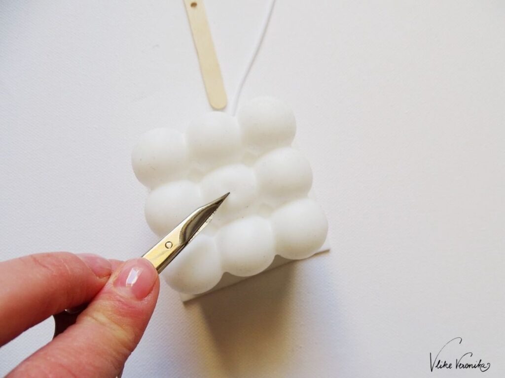 Nimm die Silikonform für die Bubble Candle und stich ein Loch mit einer Nagelschere in die Kerzenform.