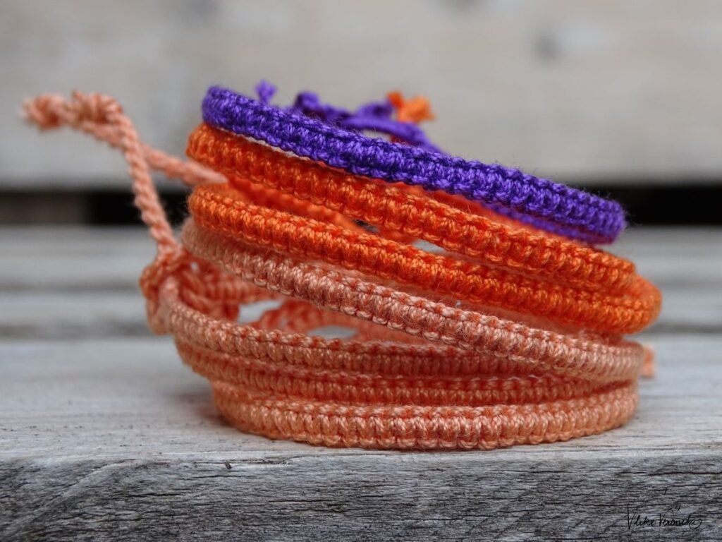 Entdecke die Anleitung für violette, orange und lachsfarbene Armbänder aus Häkelgarn mit dem Makrameekreuzknoten.