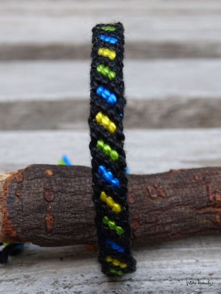Knüpfe dir Freundschaftsbänder in vier Farben wie hier das Linienmuster mit Umrandung in Schwarz, Grün, Gelb und Blau.