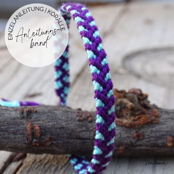 Ein Armband mit violett-türkisem Korallenmuster steht auf einer hölzernen Unterlage.